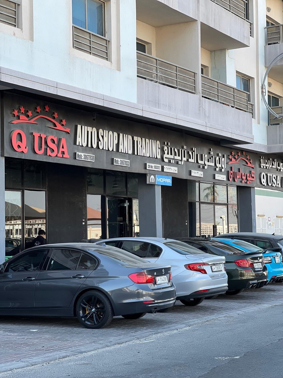 A row of daily-driver cars parked outside Q USA Auto Shop