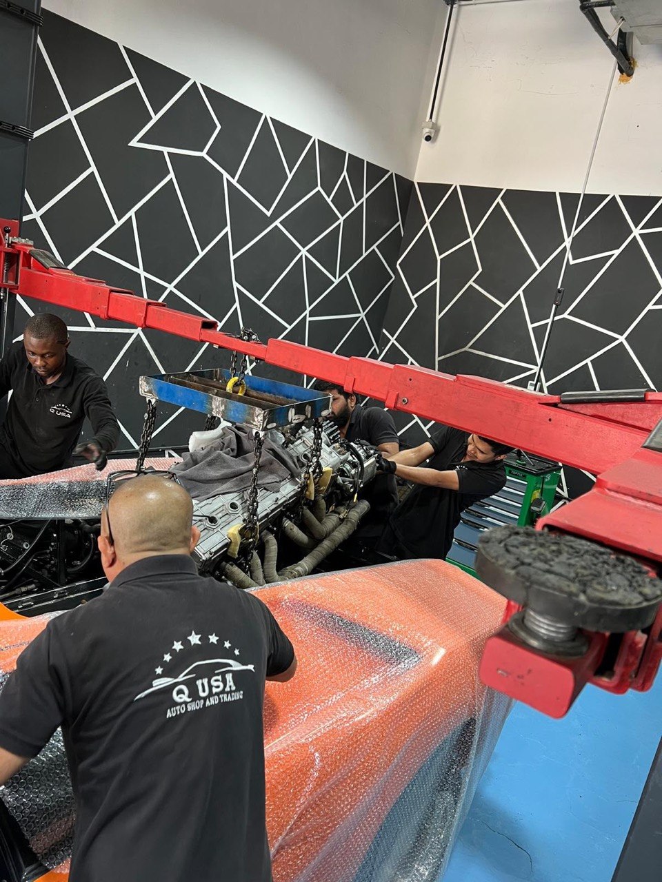 Team of technicians hoisting an engine with a crane