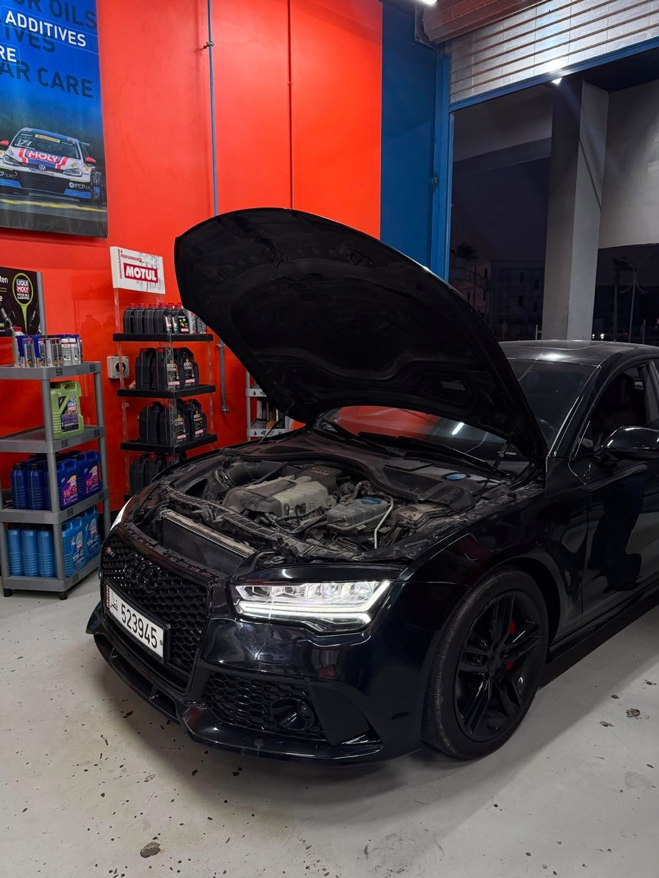 Vehicle in the workshop bay with genuine oils and parts on the shelf